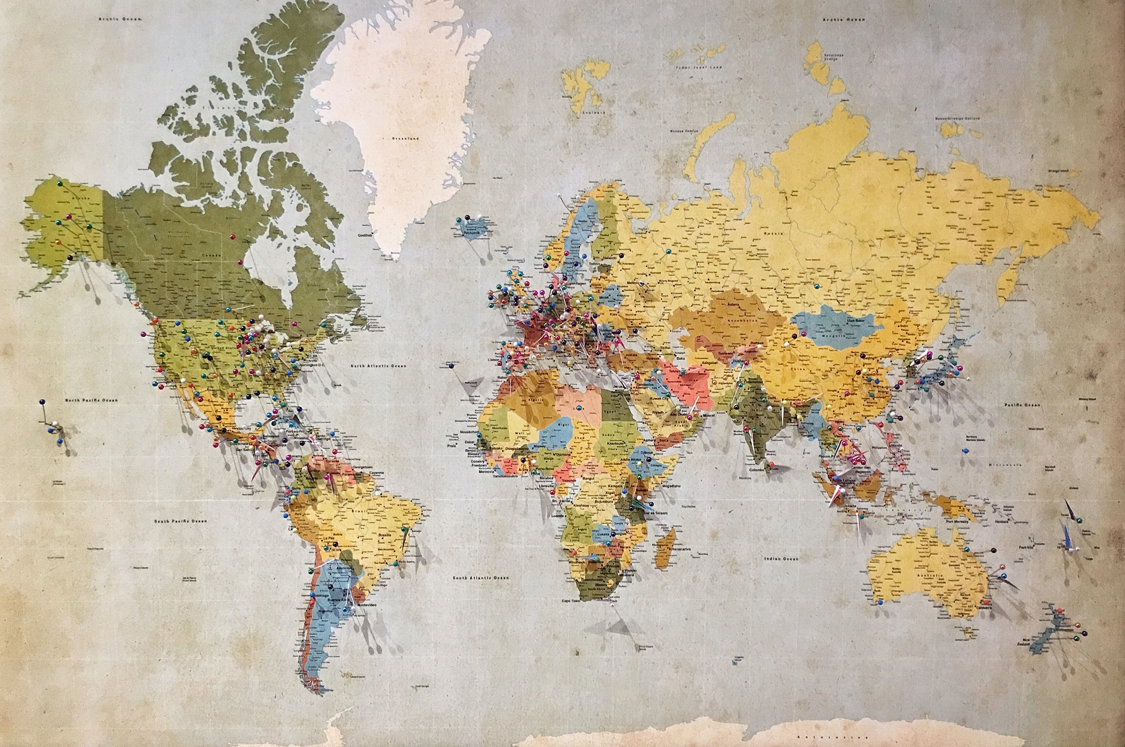 Eine bunte Weltkarte mit Pins und Fähnchen zur Markierung verschiedener Orte
