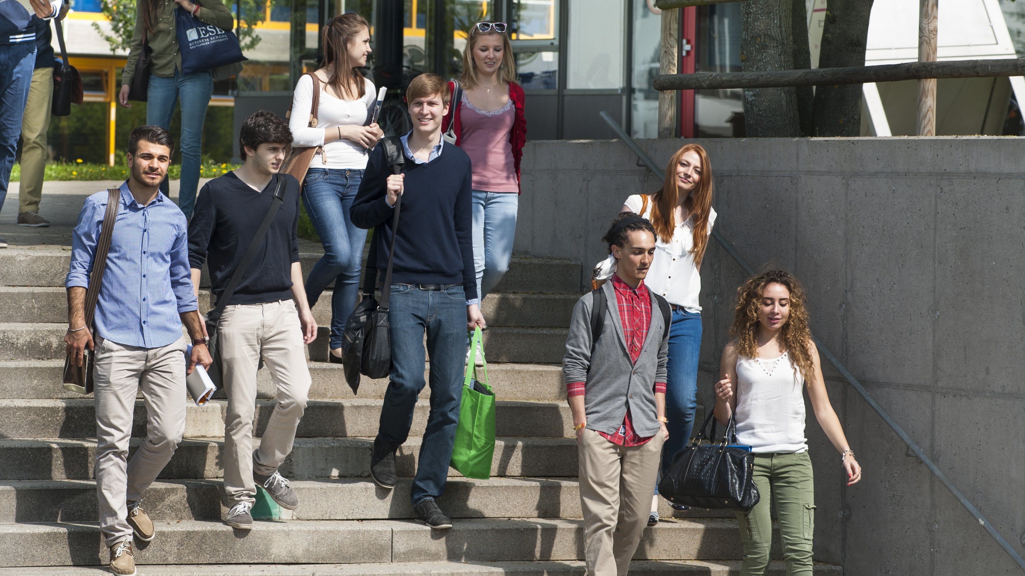 Studierende laufen Treppen am Campus hinunter und unterhalten sich