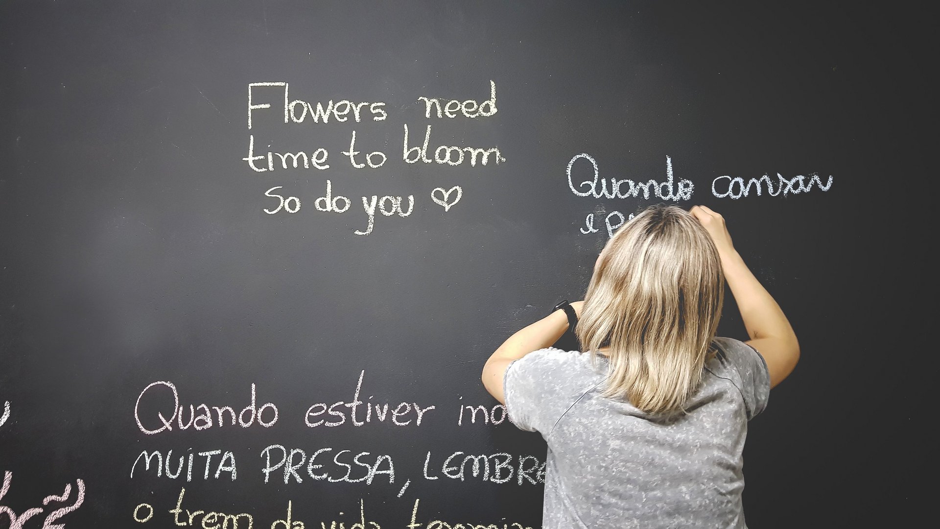 Eine Frau schreibt Sätze in verschiedenen Sprachen an eine Tafel