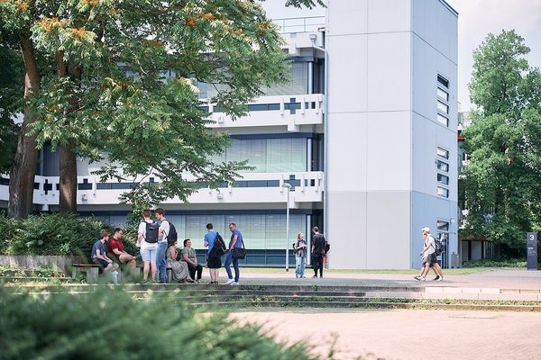 Außenansicht des Reutlinger Campus mit Studierenden und Bäumen