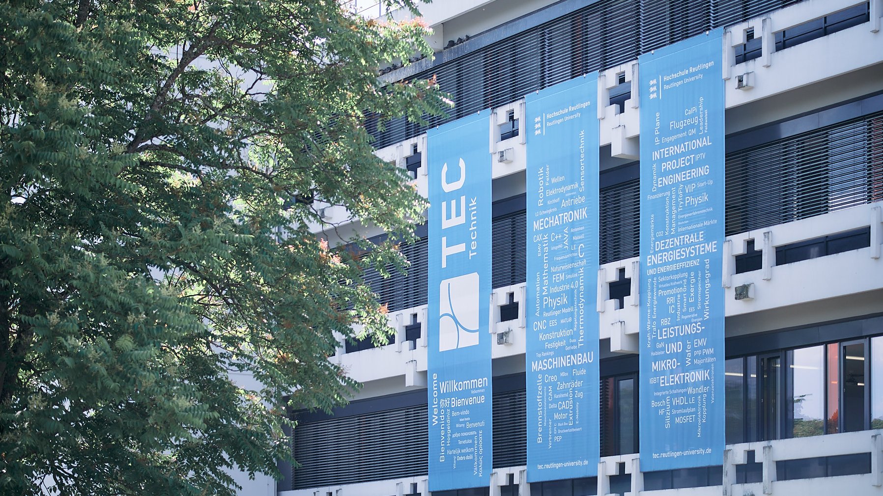 Hochschulgebäude mit drei hellblauen Bannern an der Fensterfront