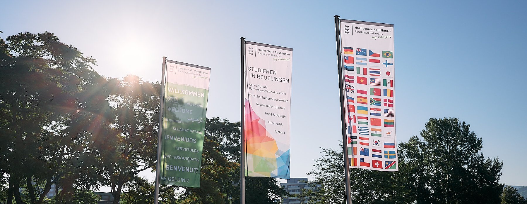 Verschiedene bunte Fahnen der Hochschule Reutlingen begrüßen Besucher am Campus