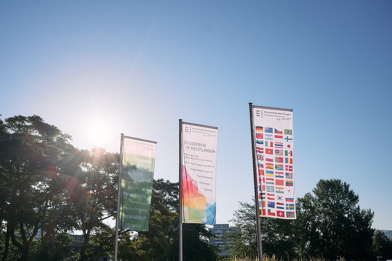 Verschiedene bunte Fahnen der Hochschule Reutlingen begrüßen Besucher am Campus