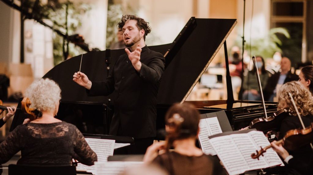 Ein Dirigent dirigiert das Hochschulorchester bei einem Konzert