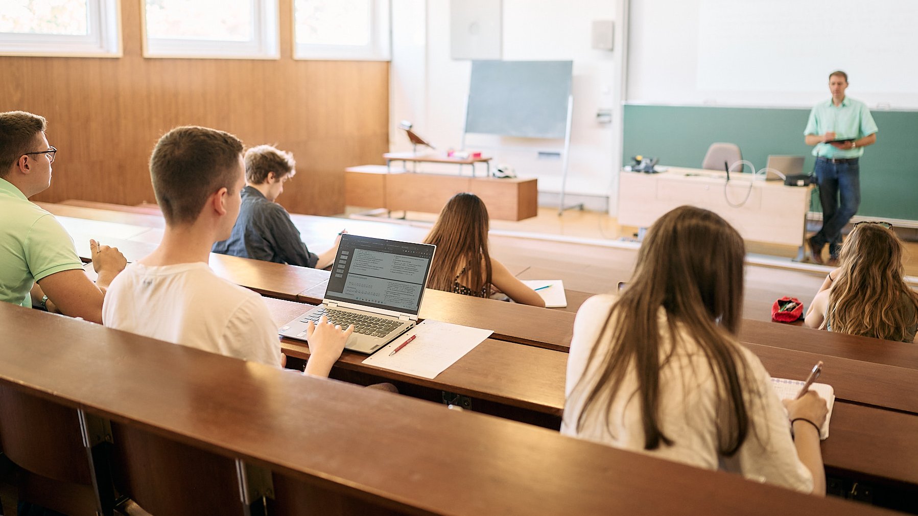 Studierende sitzen in einem Hörsaal und hören ihrem Professor zu